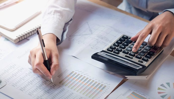 finance and accounting concept. business woman working on desk using calculator to calculate in office
